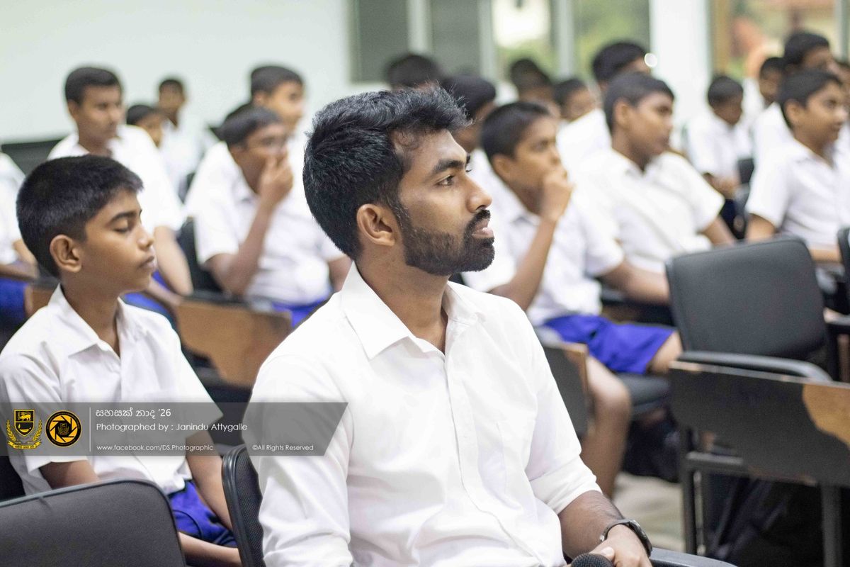 A man in a white shirt and seated students listening attentively during a workshop session